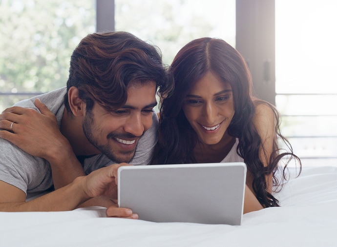 Man en vrouw lachen terwijl ze naar een tablet kijken